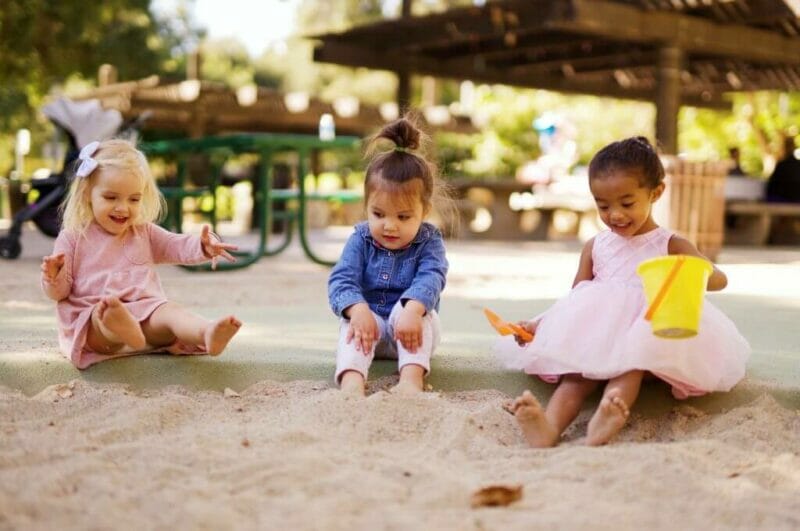 Imagem de 3 crianças brincando na areia